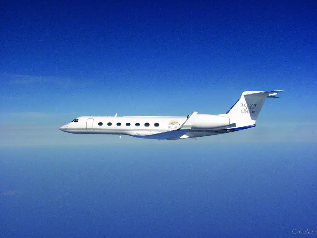 A sleek private jet flying against a clear blue sky.
