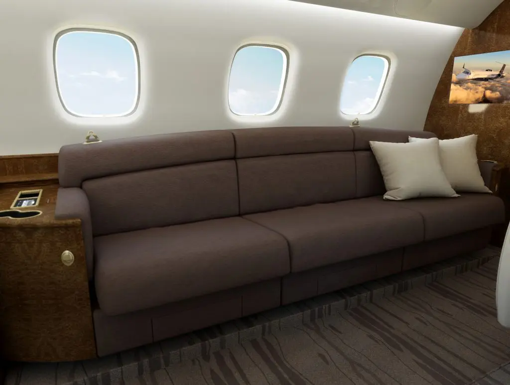 Luxury private jet interior with plush sofa and large windows.