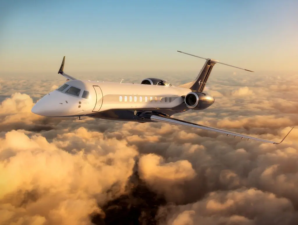 Private jet flying above the clouds during sunset.