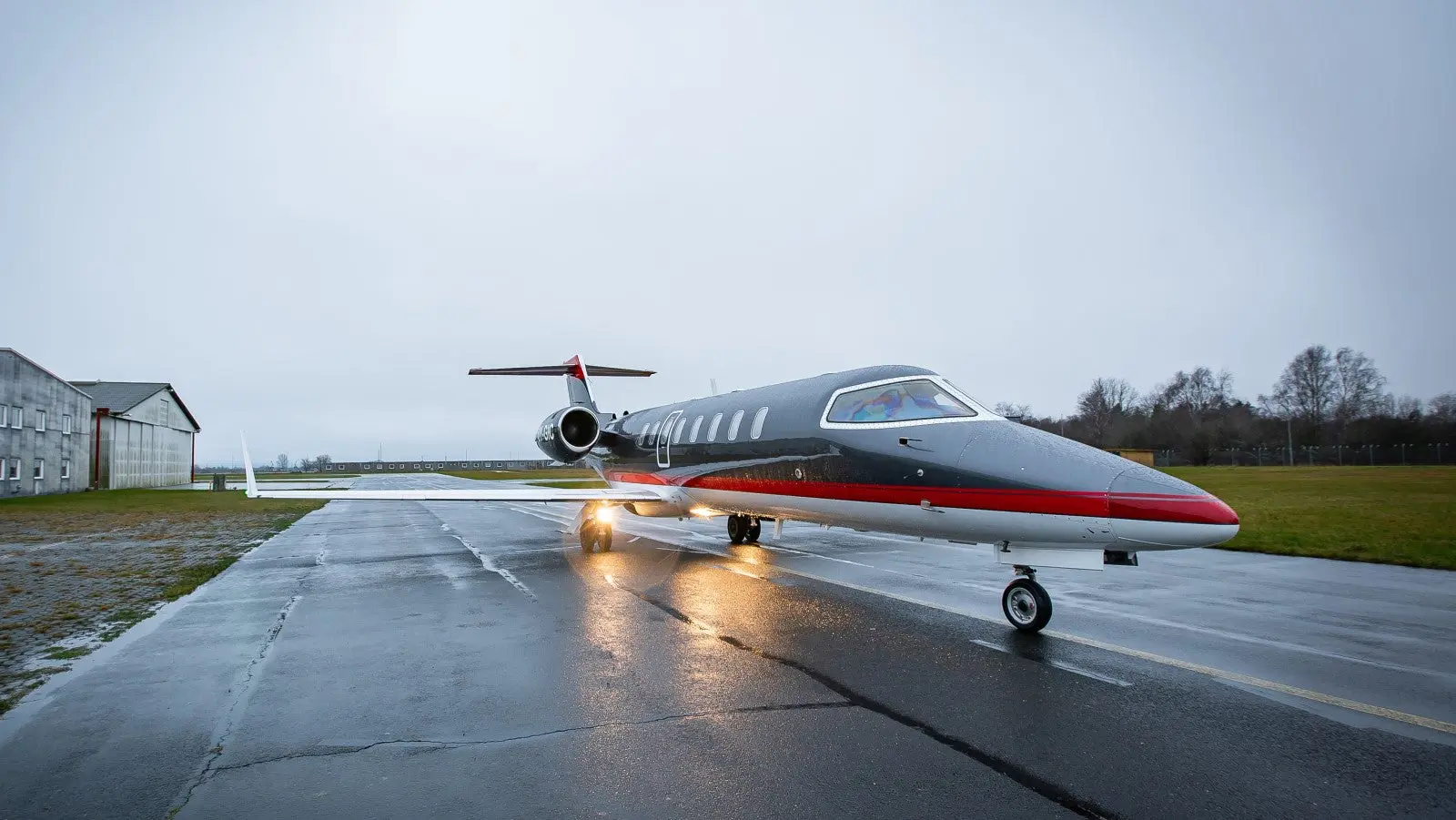 A private jet on a wet runway during a cloudy day.