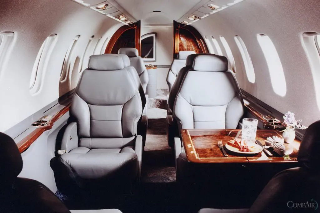 Luxurious private jet interior with leather seats and a wooden table.