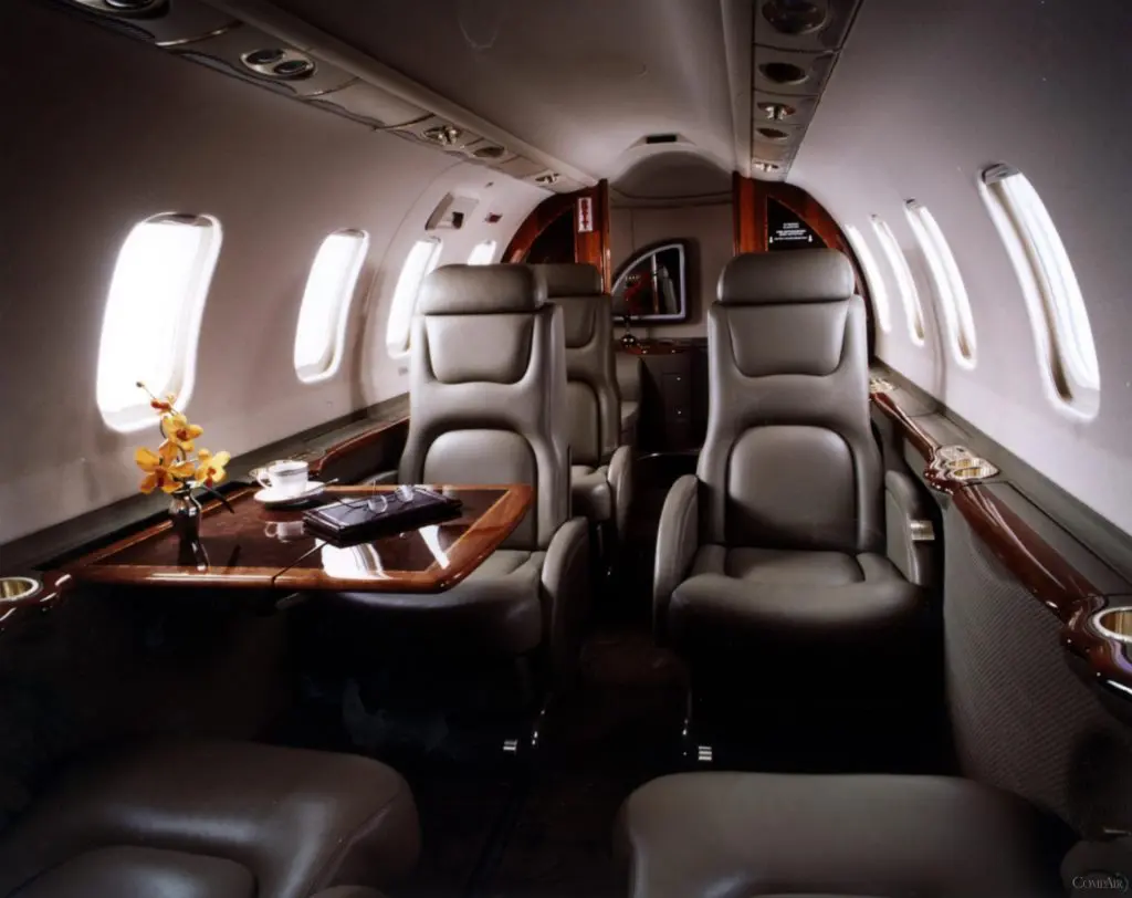Luxurious private jet interior with leather seats and wooden accents.
