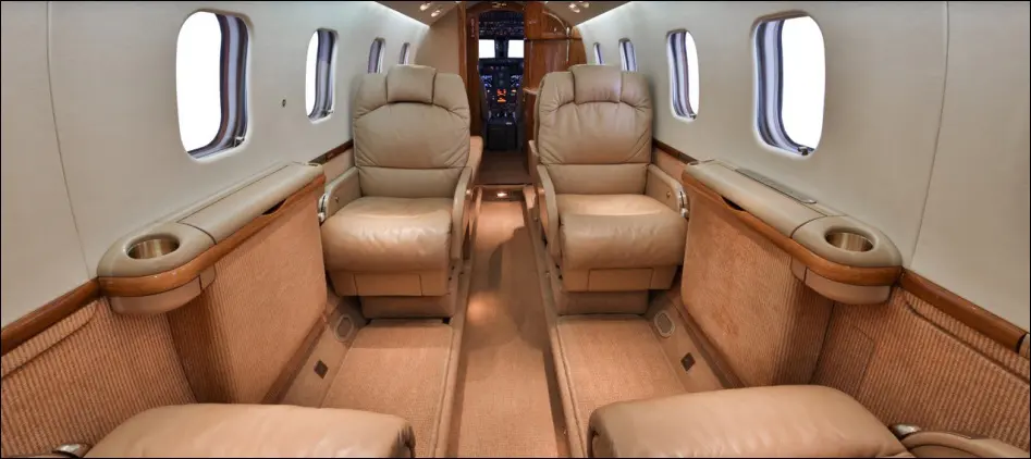 Luxurious interior of a private jet with beige leather seats.