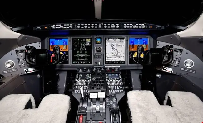 View of a modern airplane cockpit with illuminated controls and displays.