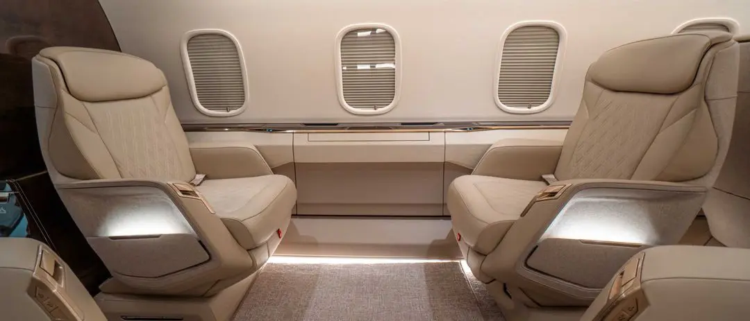 Luxurious airplane cabin with two comfortable beige seats facing each other.