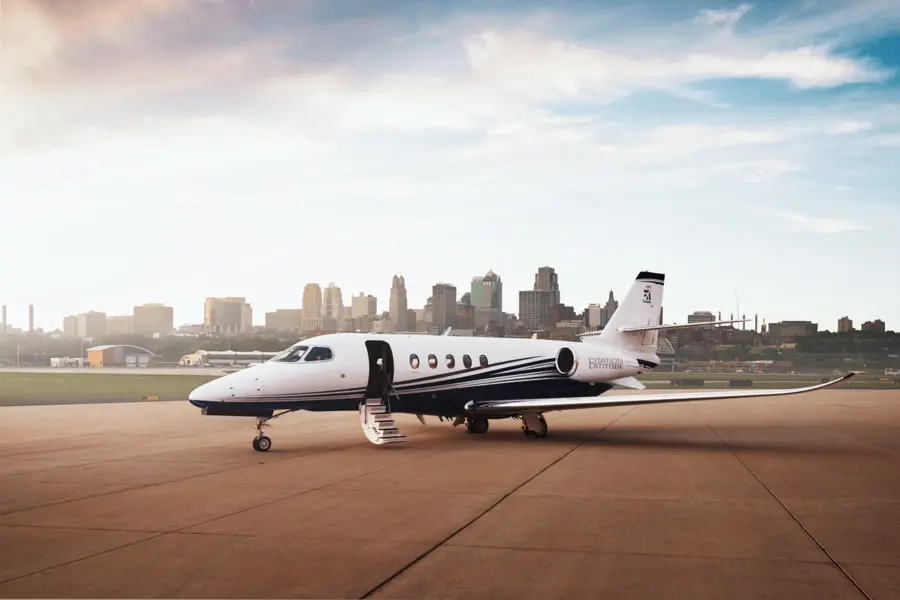 Private jet parked on runway with city skyline in background.