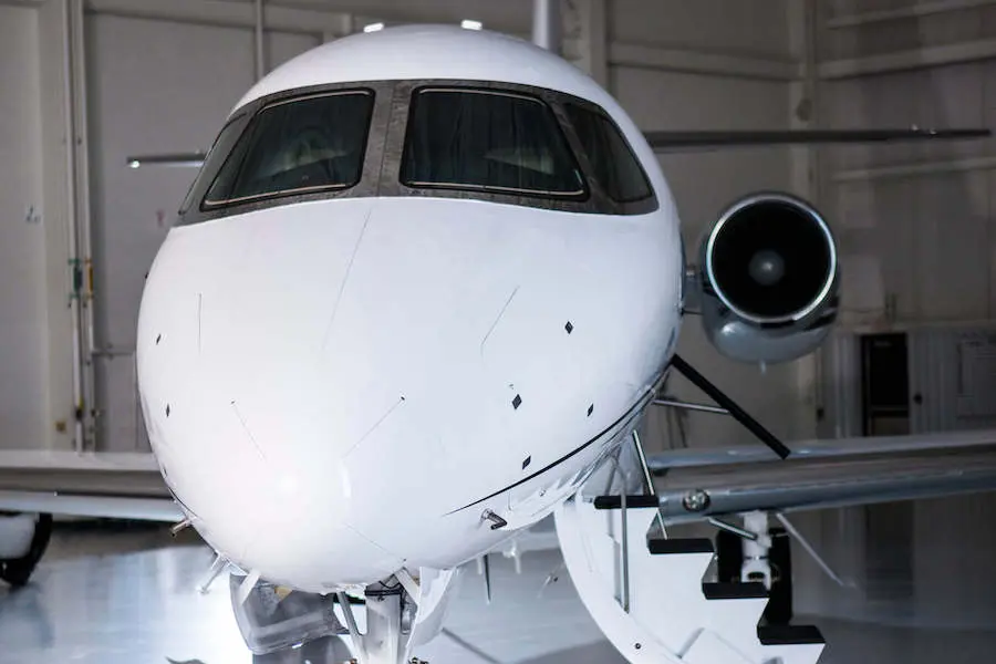 Close-up of a private jet's nose and cockpit windows inside a hangar.