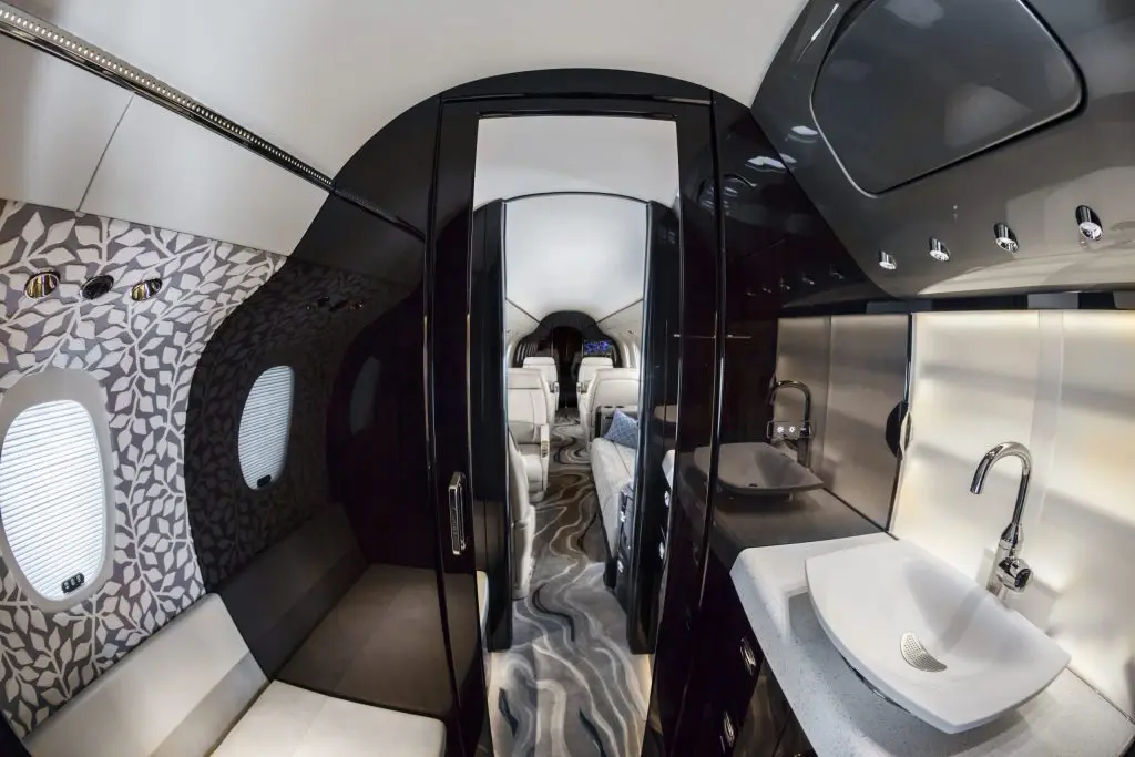Modern airplane lavatory with reflective surfaces and compact design.