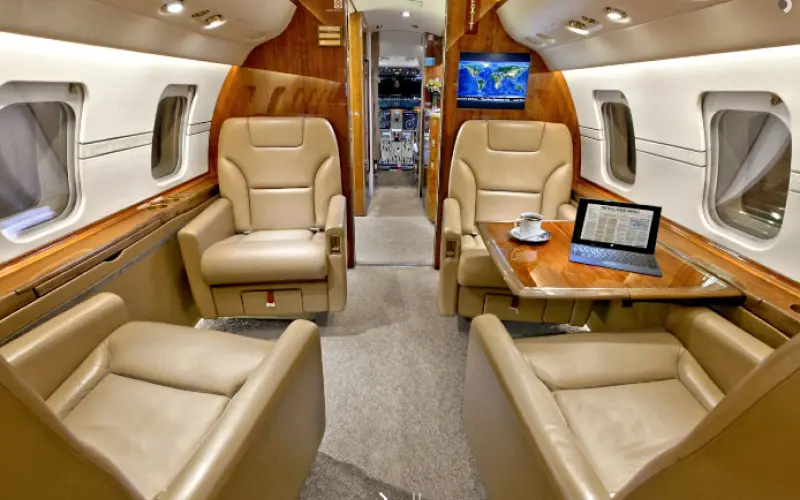 Luxurious private jet interior with leather seats and wood accents.