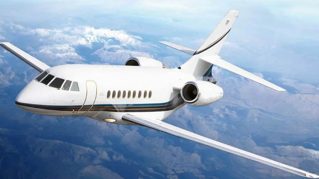 Private jet flying above the clouds with a clear blue sky.