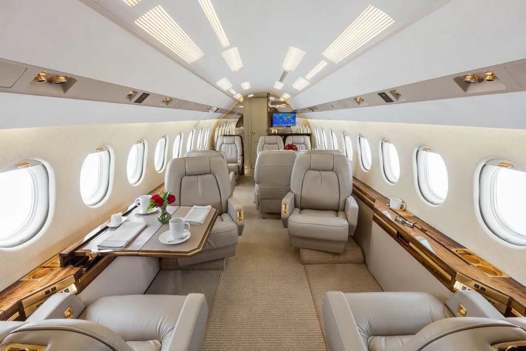 Luxurious private jet interior with spacious leather seats and wooden accents.