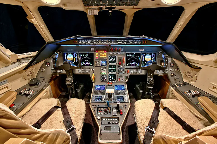 Modern aircraft cockpit with illuminated controls and displays.