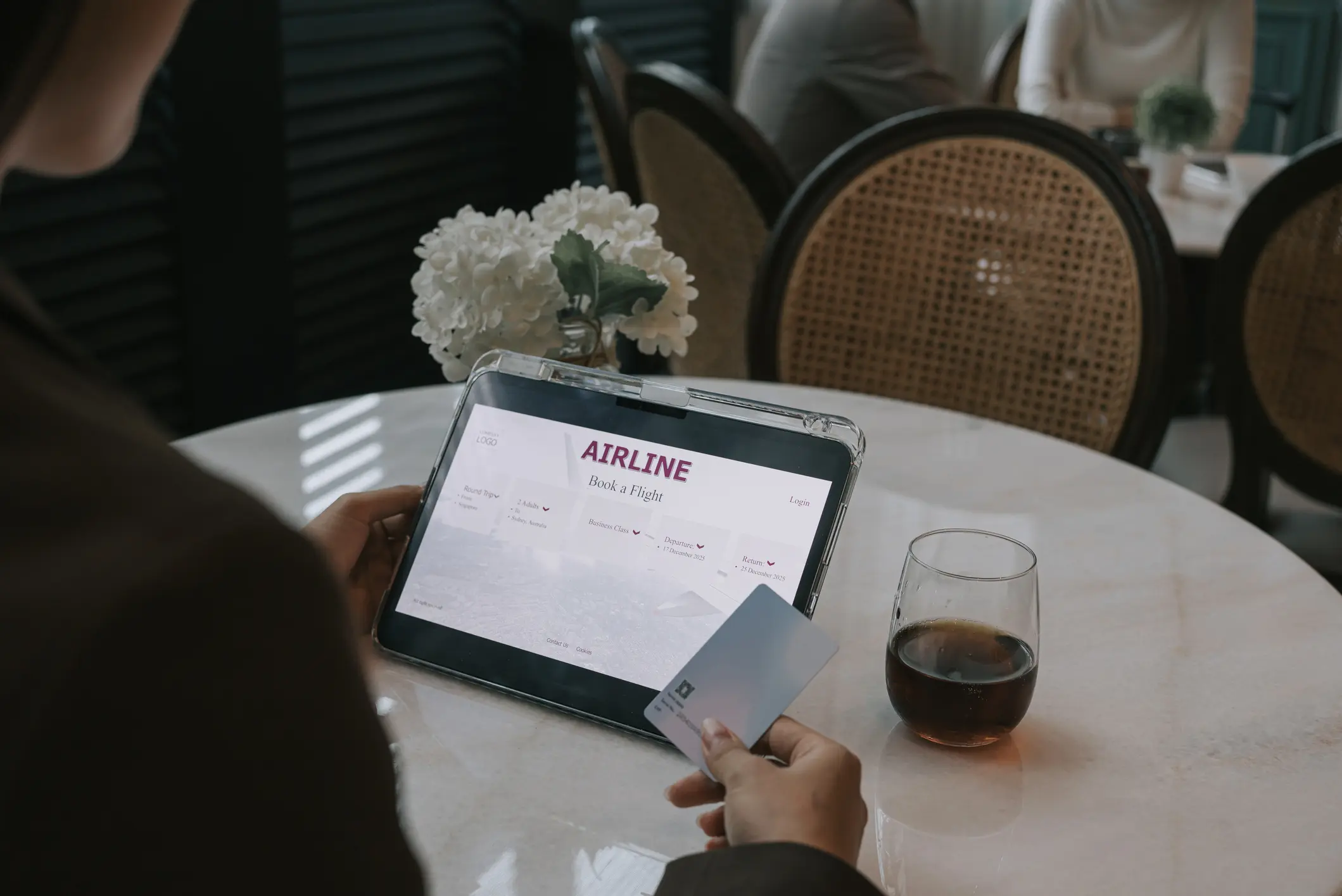Person holding a card near a tablet displaying a payment app, with coffee on the table.