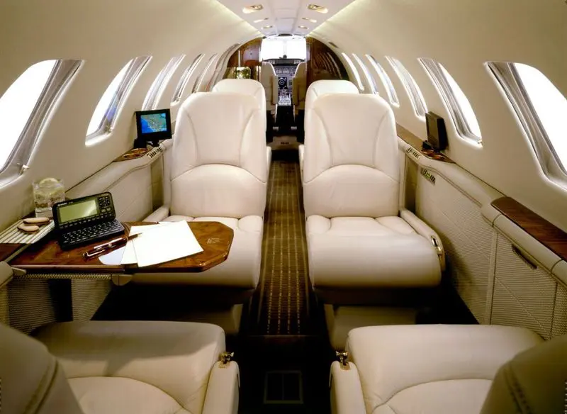 Luxurious private jet interior with plush white leather seats.