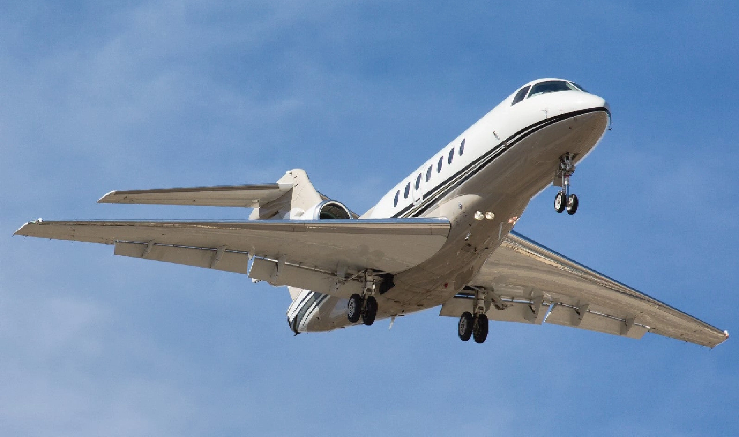 Private jet taking off against a clear blue sky.