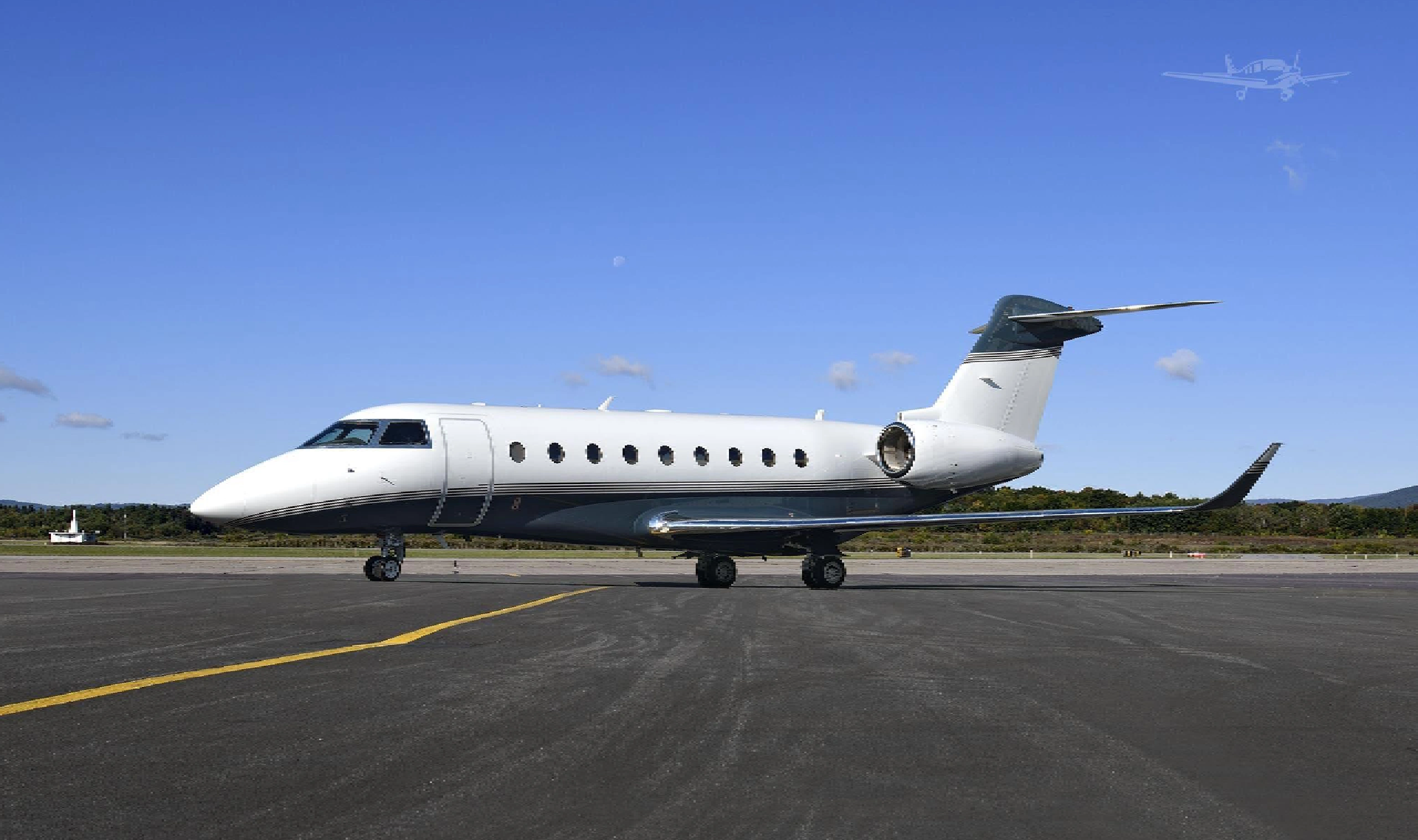 Private jet parked on the runway under clear blue sky.