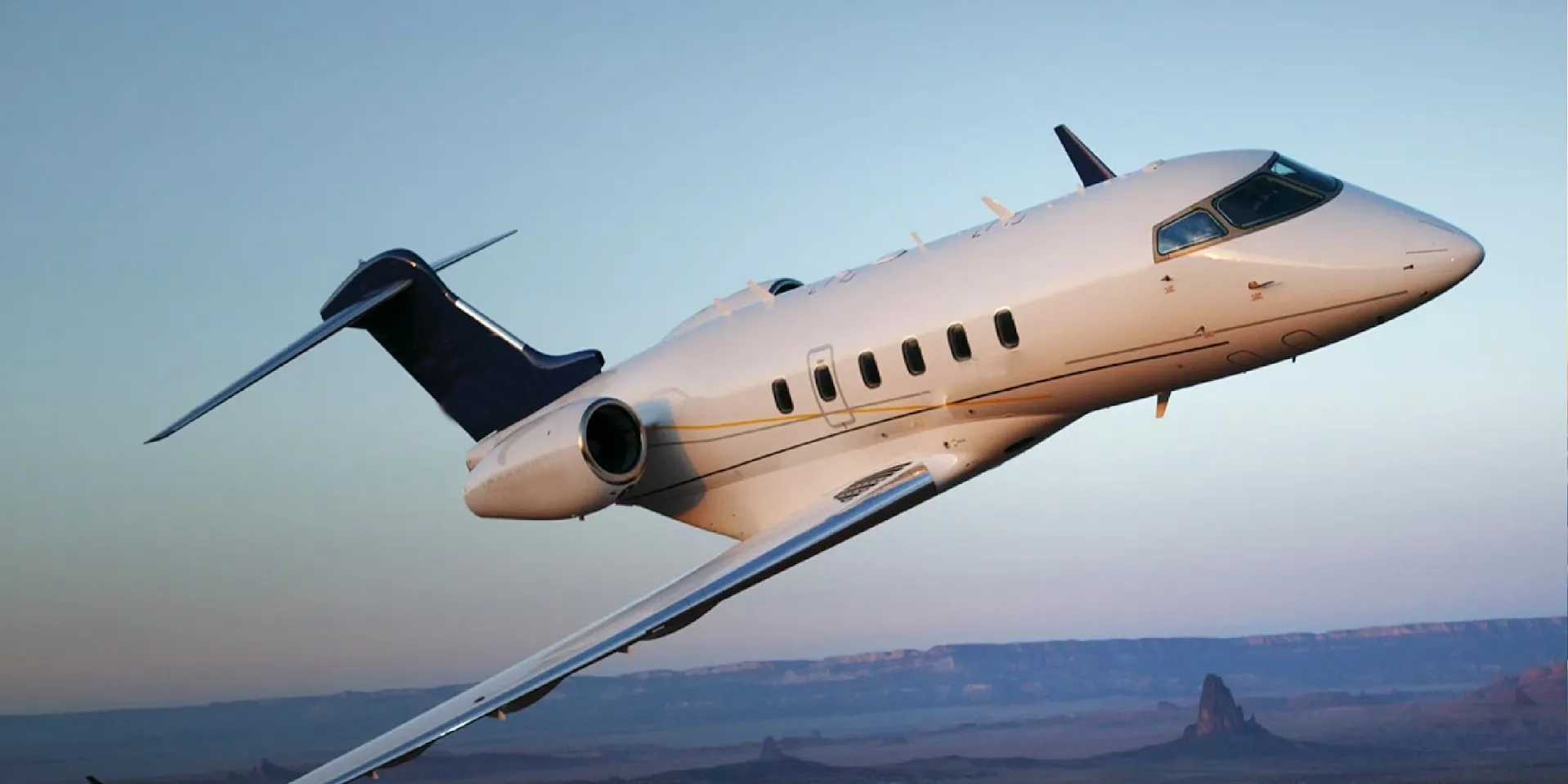 Private jet flying at sunset over a canyon.