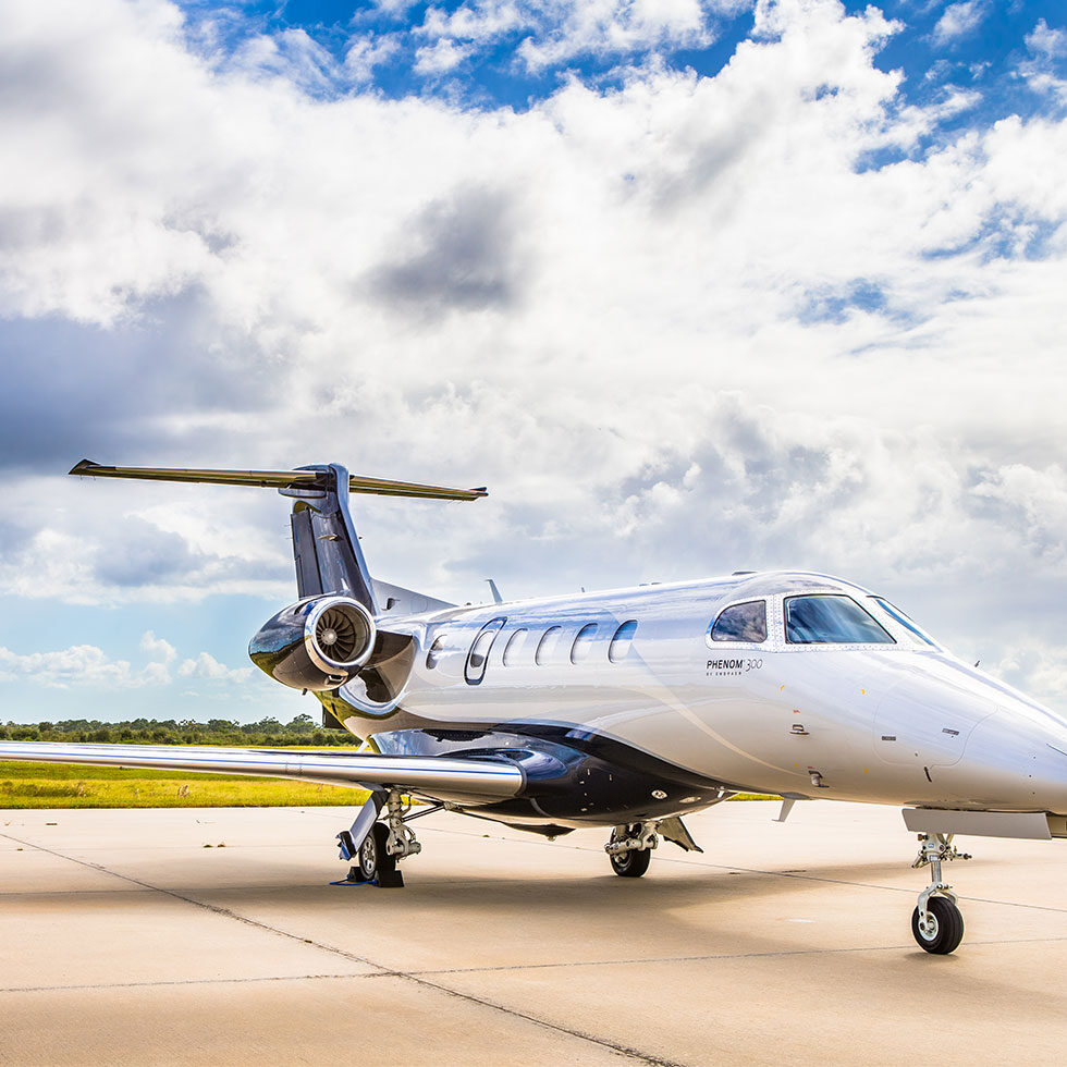 Private jet parked on a sunny airport tarmac under a blue sky.