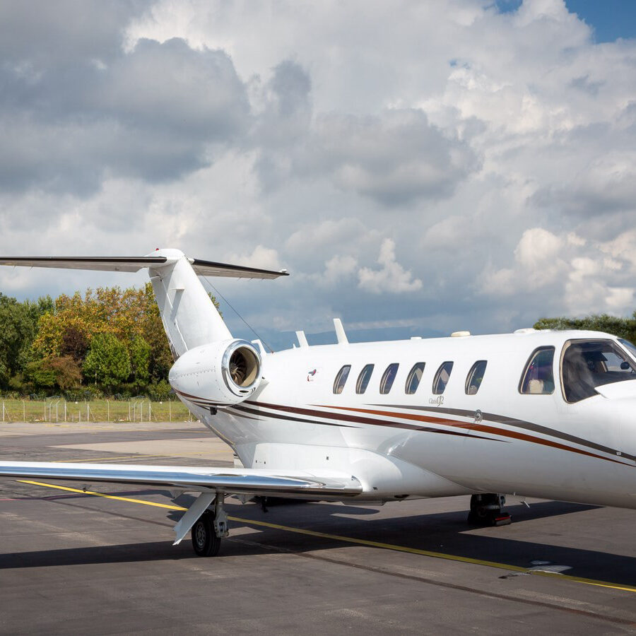 A small private jet parked on a runway under a cloudy sky.