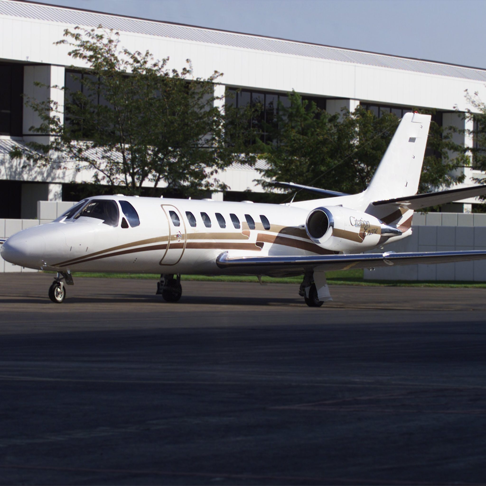 Private jet parked on an airport tarmac near a building.