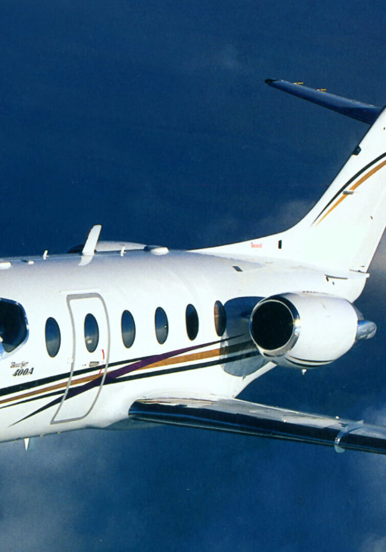 A sleek private jet flying against a deep blue sky.