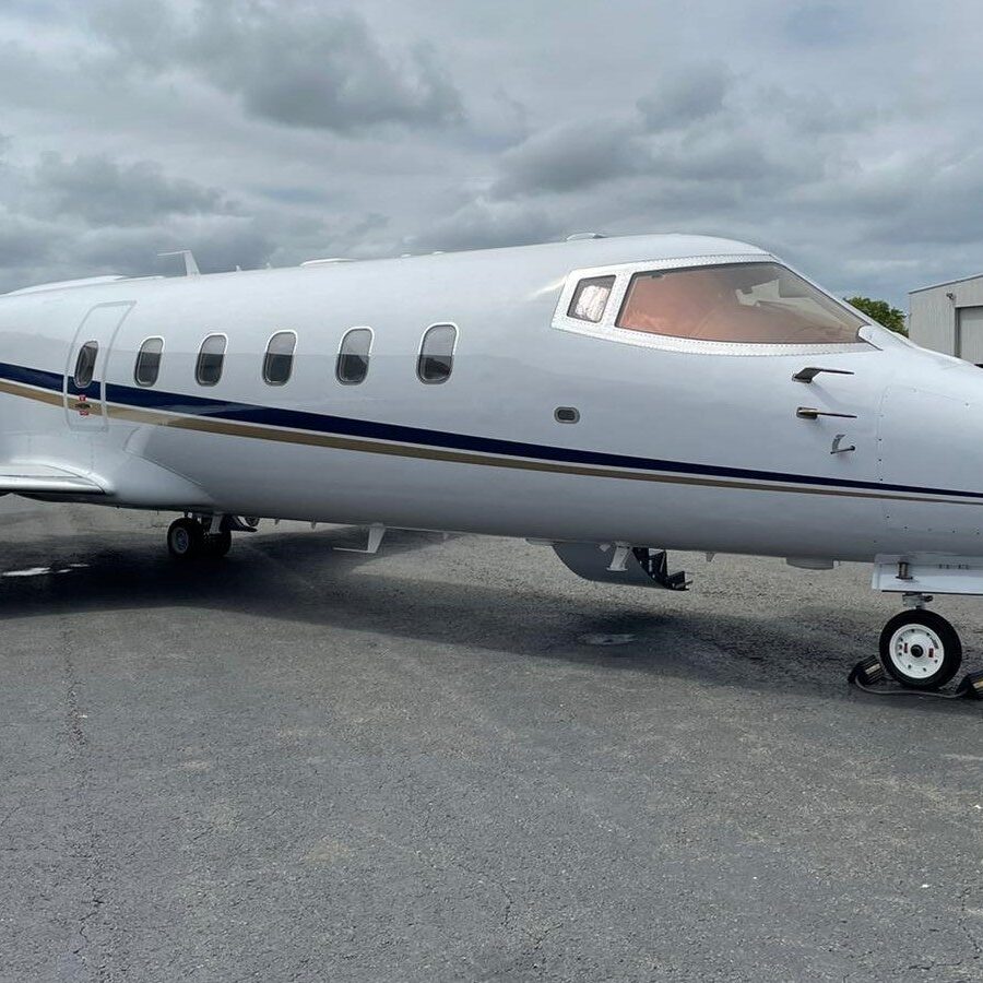 A sleek private jet parked on a cloudy day at the airport.