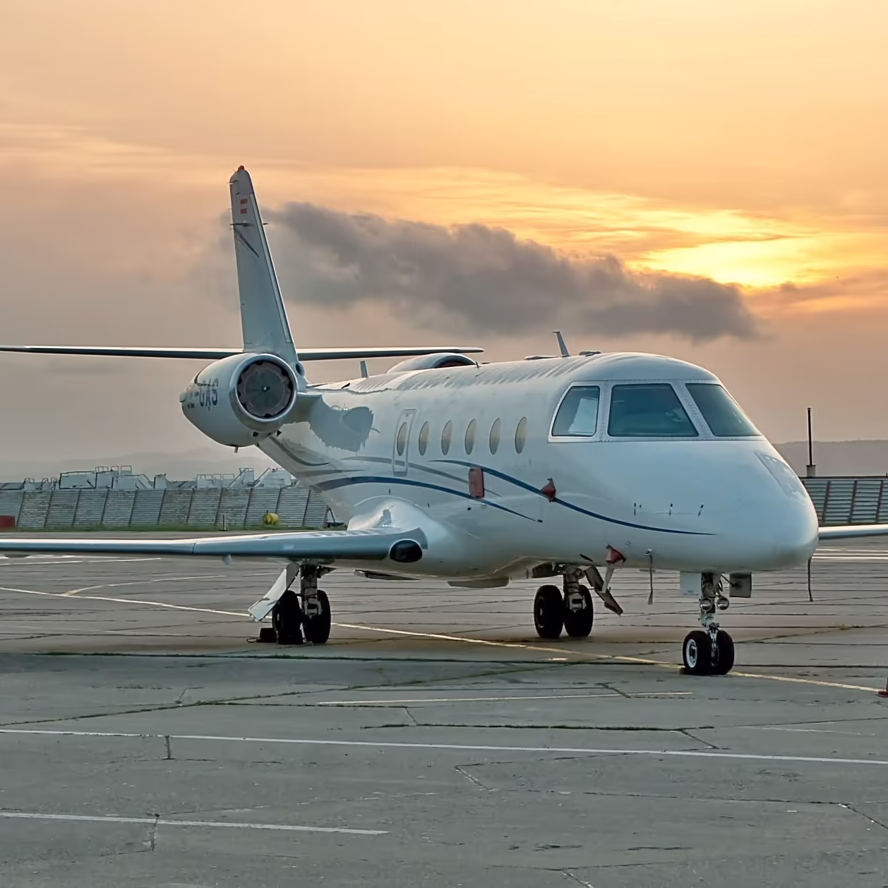 Private jet parked on runway during sunset.