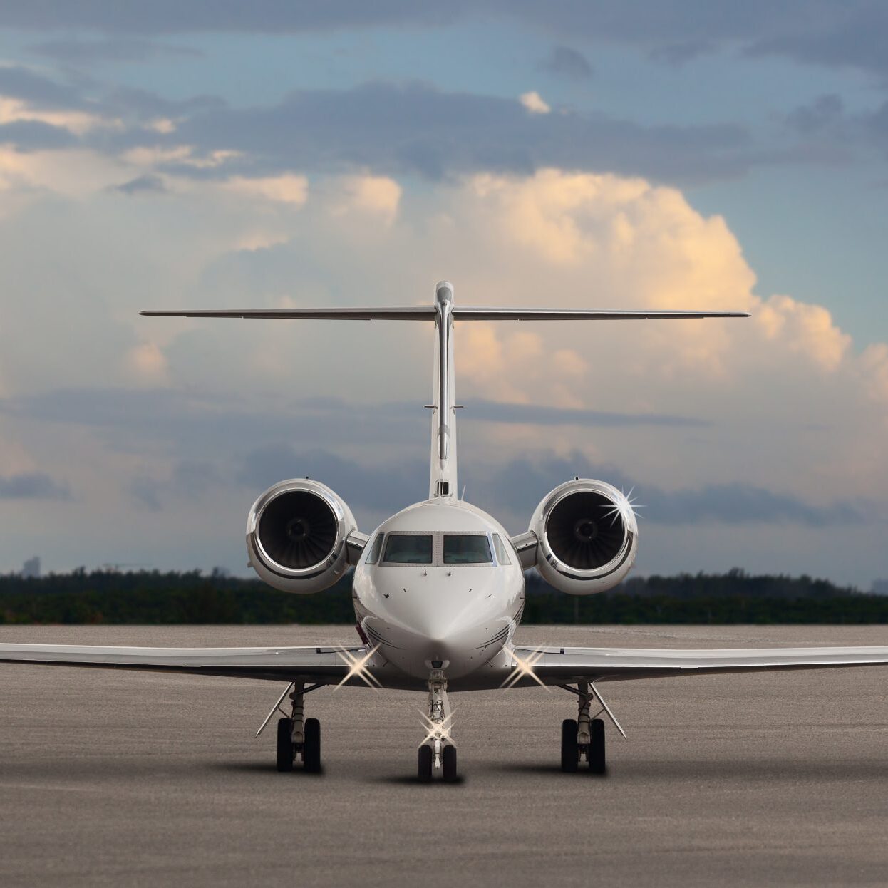 Private jet parked on airport runway under a cloudy sky.