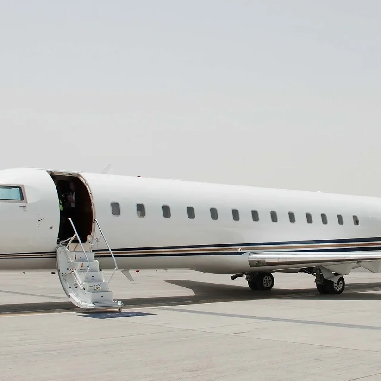 Private jet on the tarmac with its door open and stairs extended.
