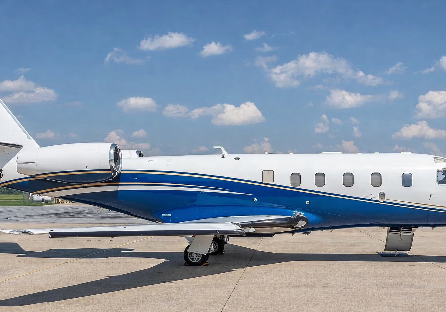 Private jet parked on a sunny runway under a blue sky.
